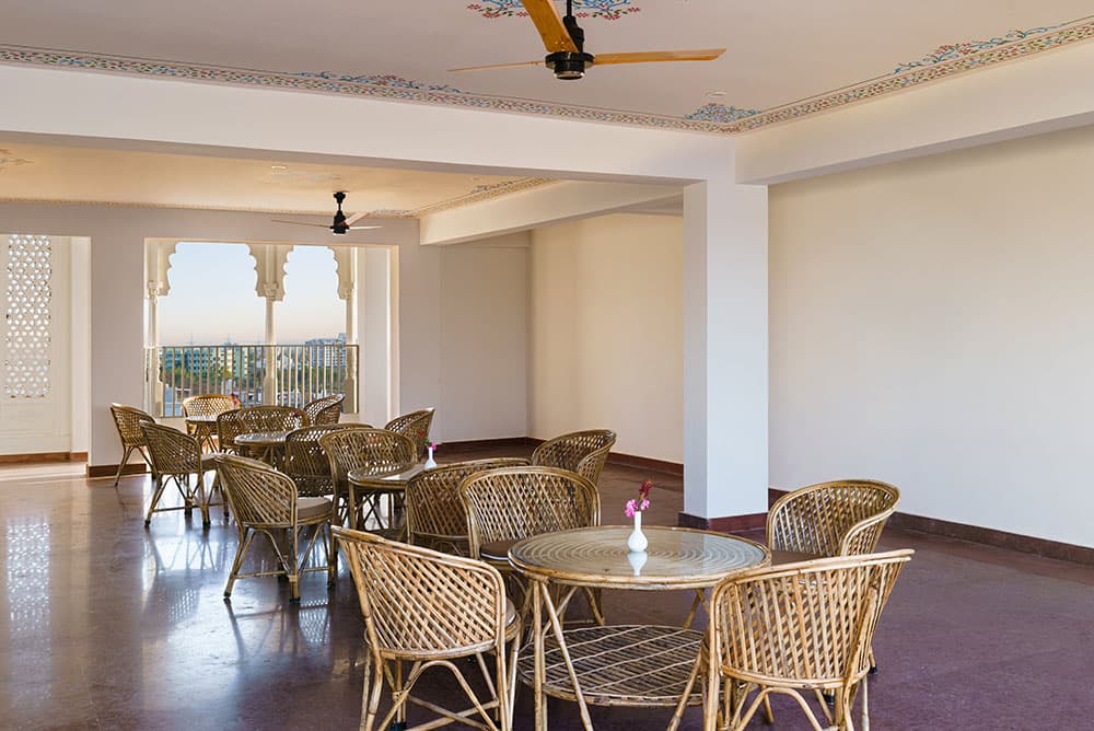 The Roof Top Cafe with wicker chairs, glass-topped tables and a cusped-arch window