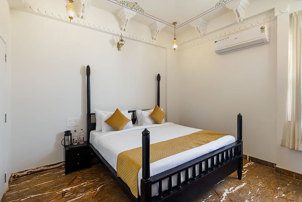 Deluxe Room with a dark-wood four-post bed, gold accents and marble floors
