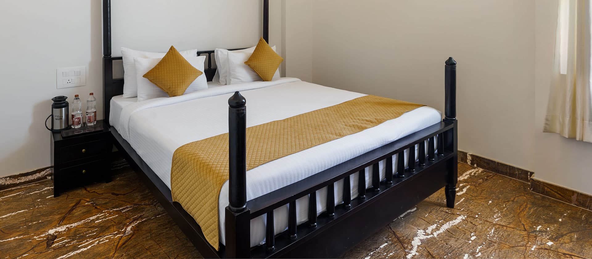 Deluxe Room bed dressed in white linen with a mustard-gold runner and cushions