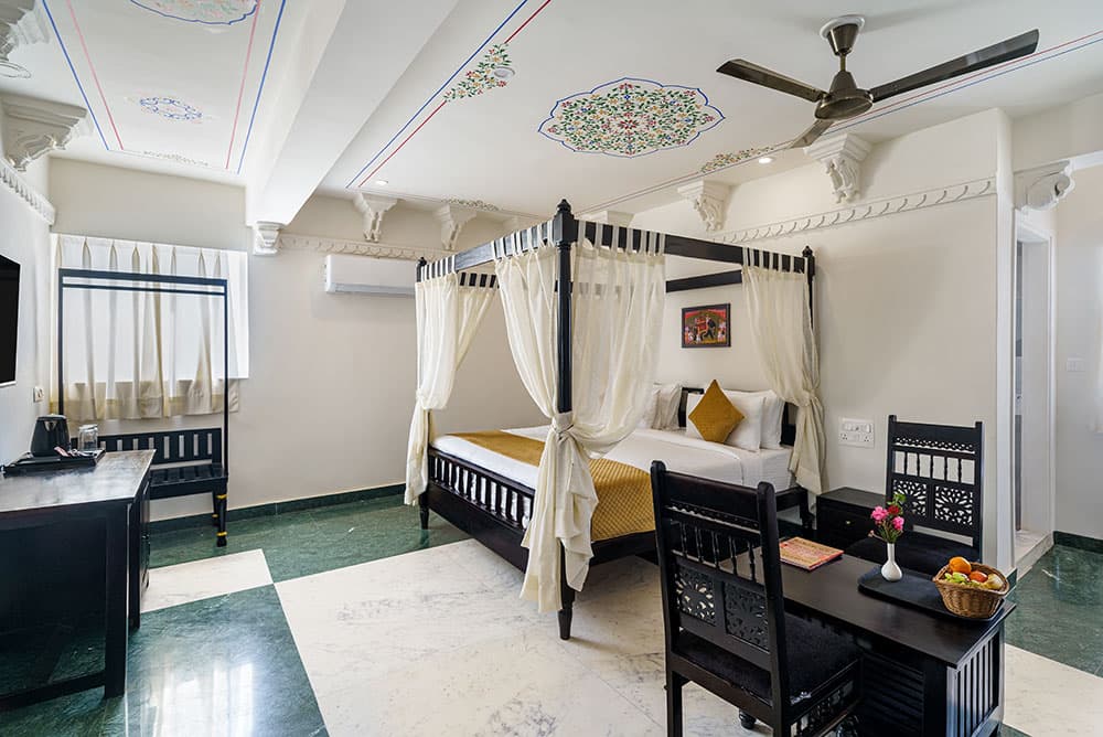 Guest room with a four-poster bed, green marble floor and a writing desk