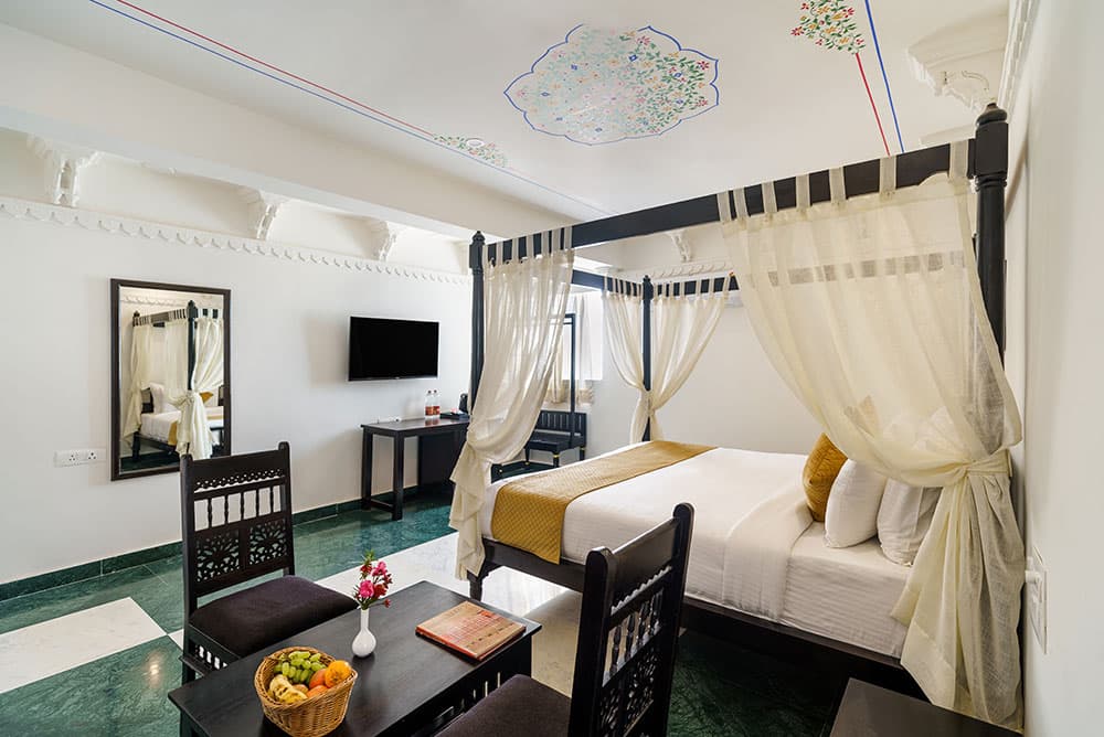 Guest room with a four-poster bed, a fruit bowl on the side table and a painted ceiling medallion