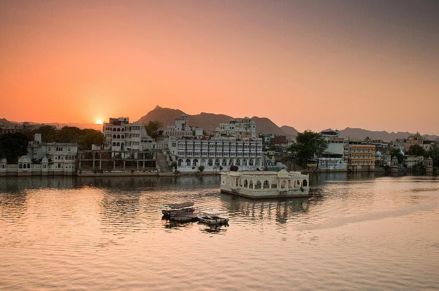 Sunset over Lake Pichola with boats on the water and the Aravalli hills