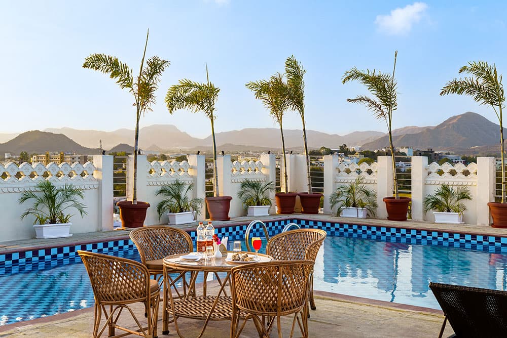 Wicker dining set beside the rooftop pool under a clear sky