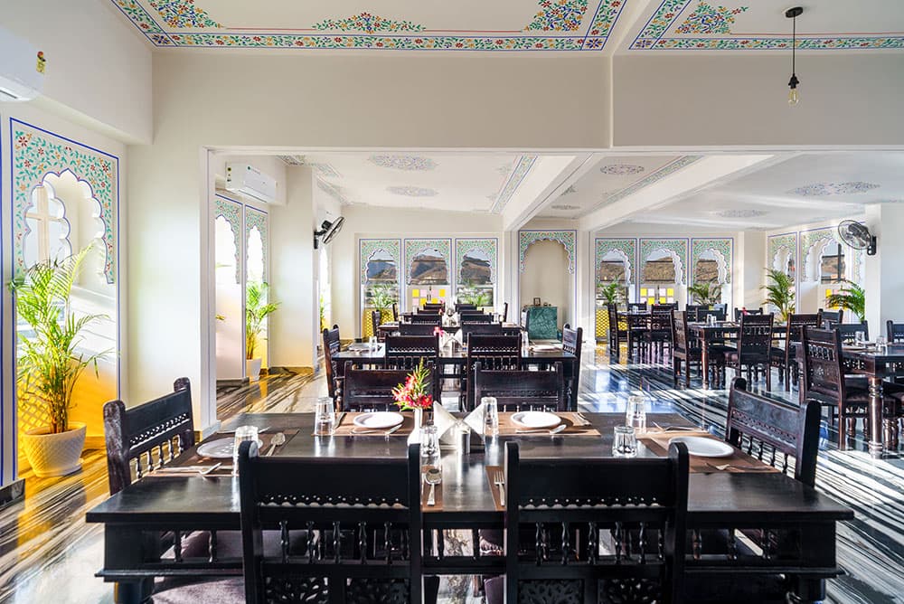 Restaurant table laid for dinner beneath painted floral ceiling borders