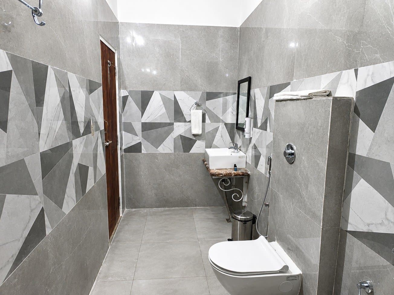 Suite Room bathroom with grey geometric wall tiles, a basin on a marble shelf and a wall-hung toilet