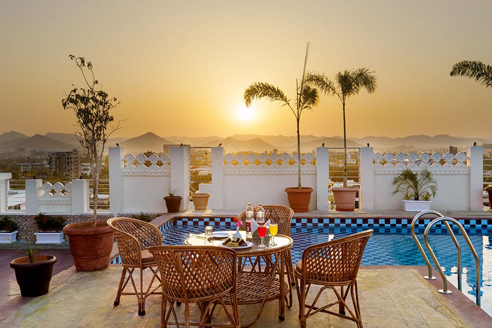Poolside table set with drinks as the sun sets over the hills