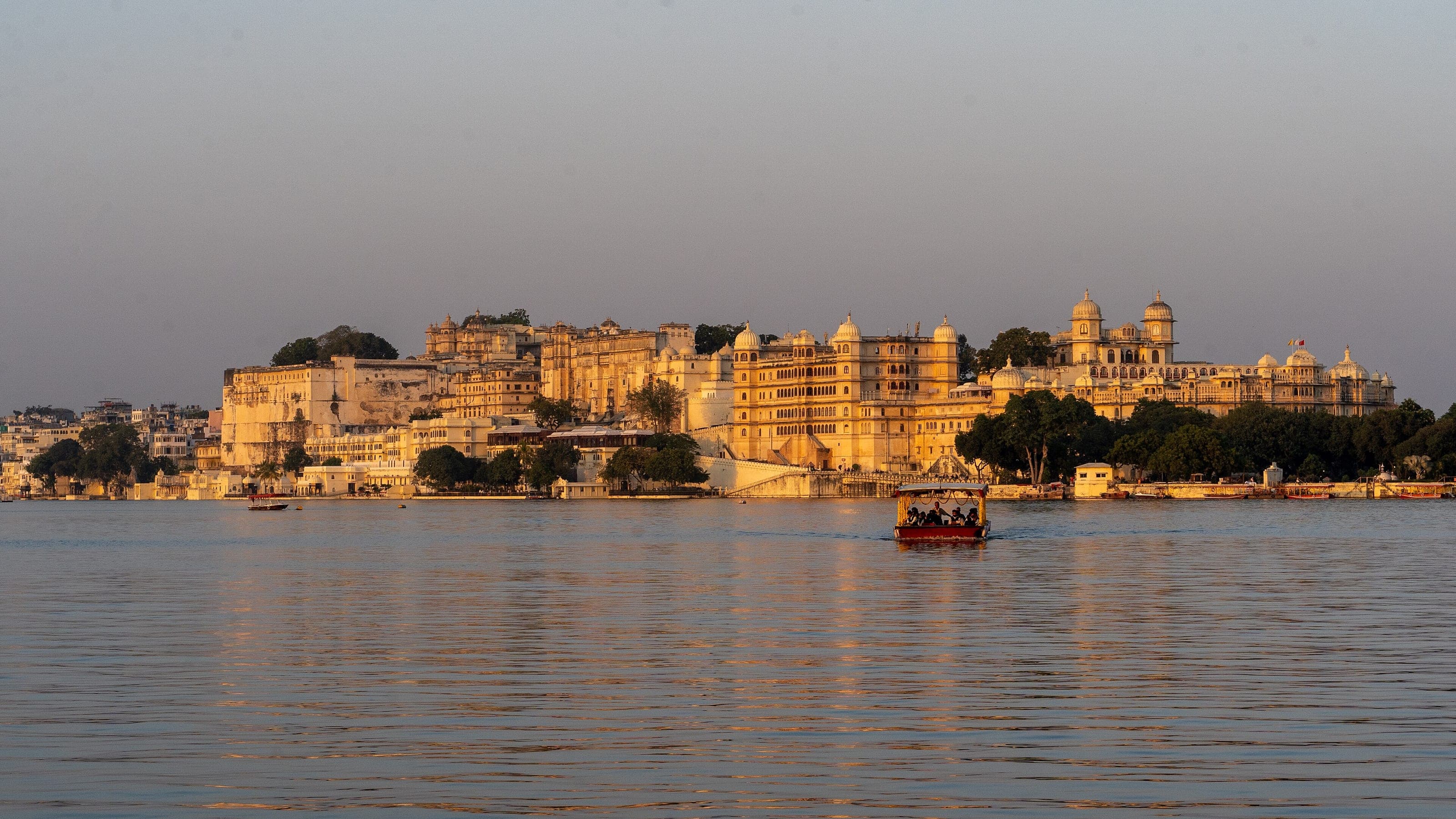 The City Palace glowing at golden hour above Lake Pichola, Udaipur