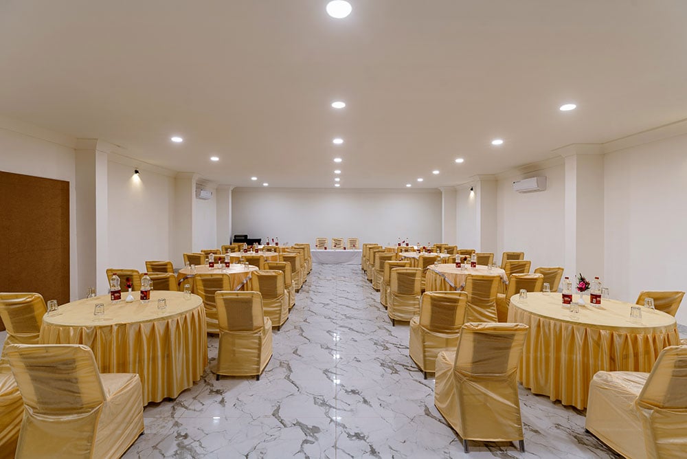 Banquet hall set for a celebration with rows of gold-dressed tables