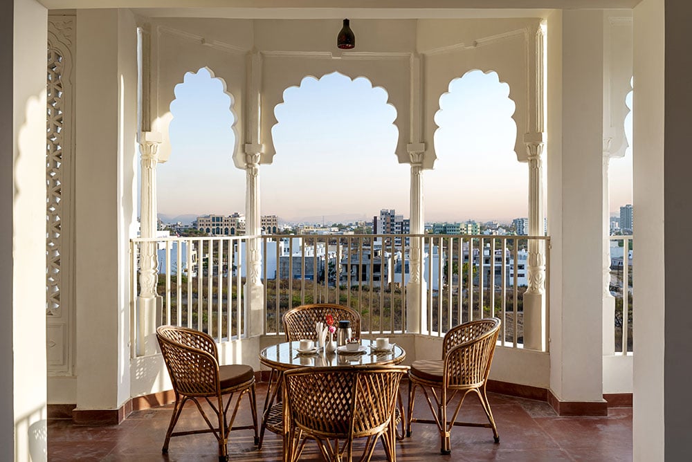 Wicker table for four set inside a jharokha of cusped arches overlooking Udaipur