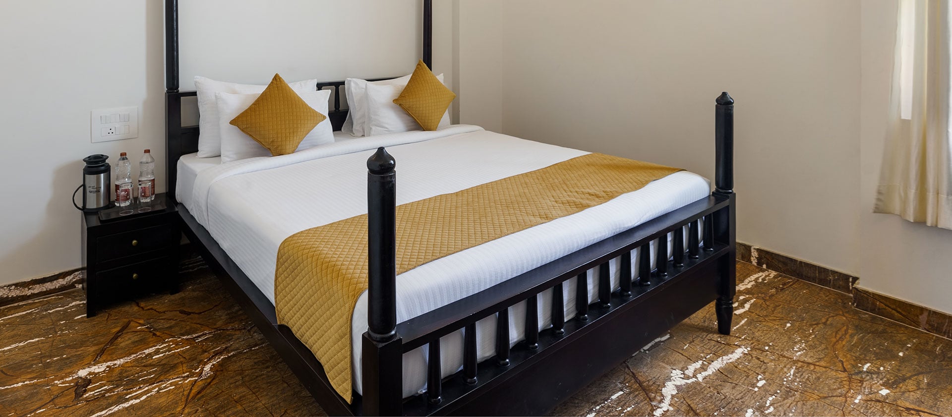 Deluxe Room bed dressed in white linen with a mustard-gold runner and cushions