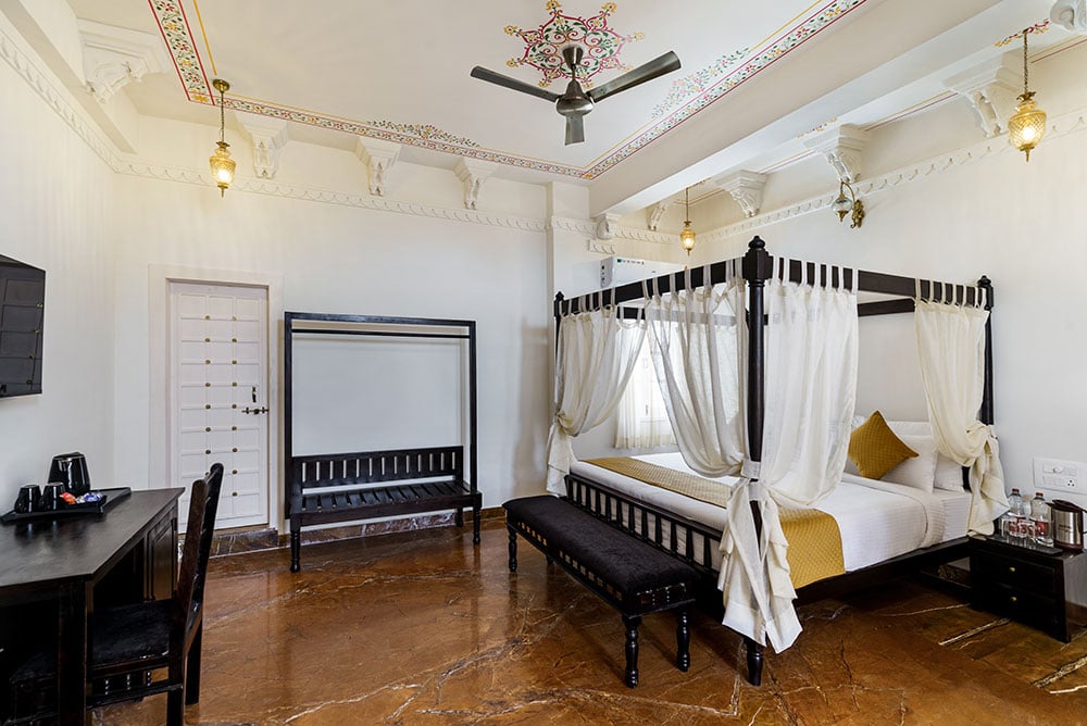 Super Deluxe Room with a dark-wood four-poster bed, sheer canopy curtains and a painted ceiling border