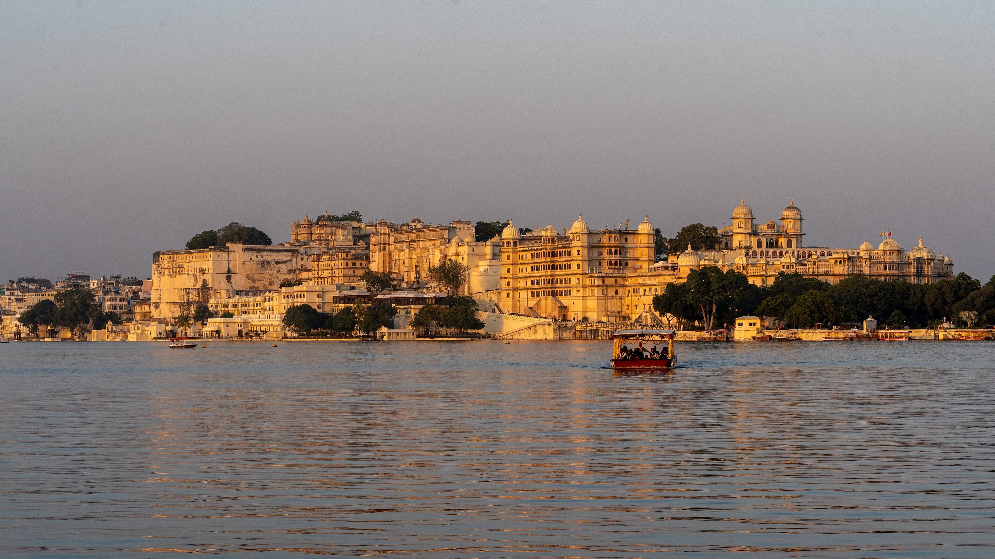 The City Palace glowing at golden hour above Lake Pichola, Udaipur