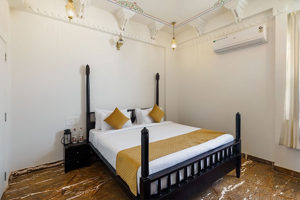 Deluxe Room with a dark-wood four-post bed, gold accents and marble floors