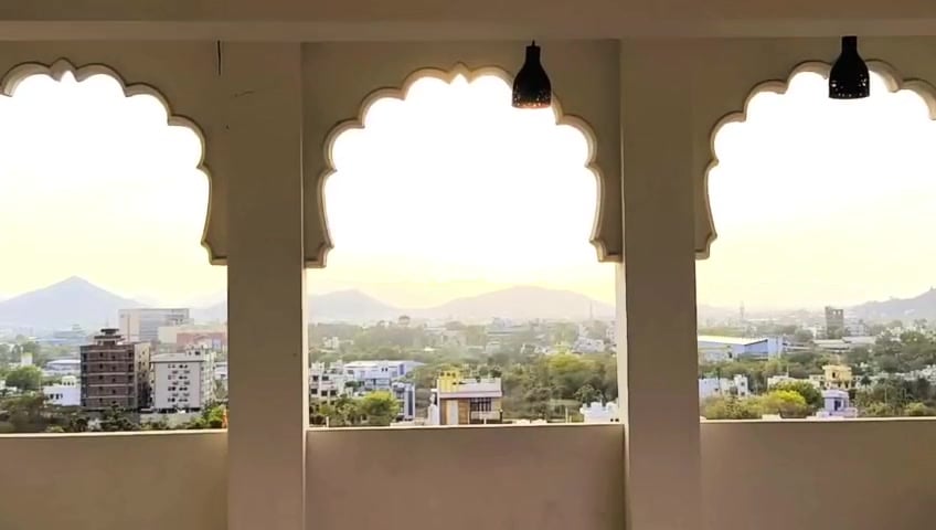 White cusped arches at Hotel Rudra Kripa framing a view of the Aravalli hills